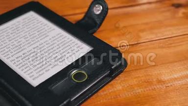 一个箱子里的电子书放在木桌上。 电子墨水屏幕显示书籍文本